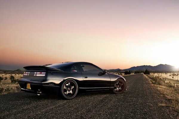 Black 2-door sedan on a country road