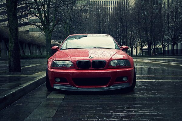 BMW E46 rouge dans une ville pluvieuse