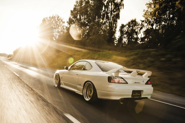 White nissan rushing to meet the sun