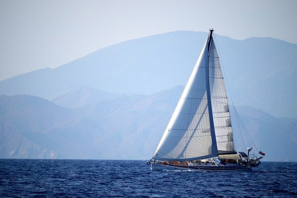 Vor dem Hintergrund der Berge - eine Yacht, die auf dem Meer schwimmt