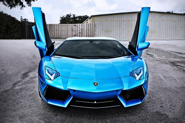 Автомобиль Lamborghini синего цвета с открытыми дверями