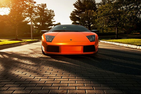 Lamborghini naranja en adoquines a la sombra