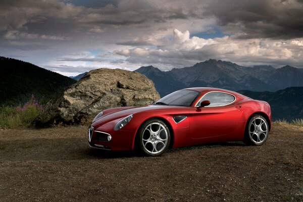 Alfa Romeo rojo en el fondo del paisaje de montaña