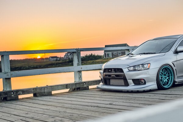 Mitsubishi grigio sul ponte che si affaccia sul tramonto