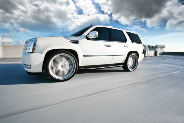 El Cadillac escalade blanco monta rápido tiene las tapas de las ruedas borrosas