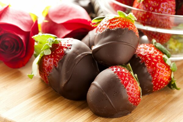 Chocolate-covered strawberries and roses on the table