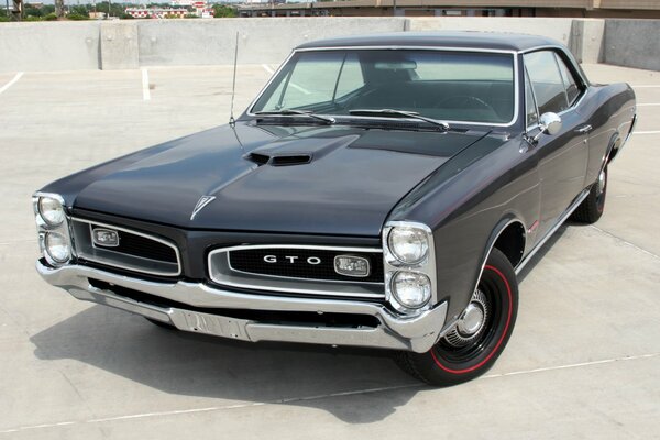 A black pontiac stands in the parking lot of the Ford