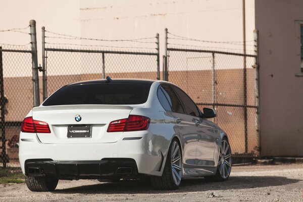 White BMW tinted stands behind the fence