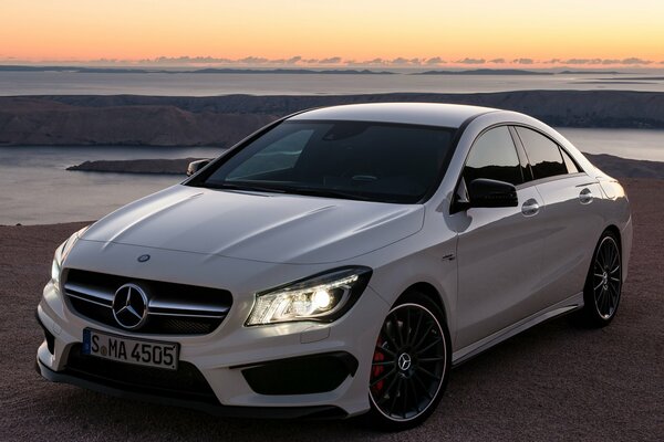 Mercedes blanco en la naturaleza con los faros incluidos