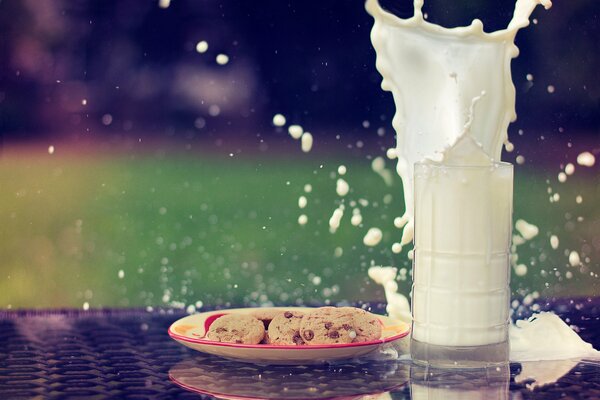 A plate of cookies and a glass of milk with a splash