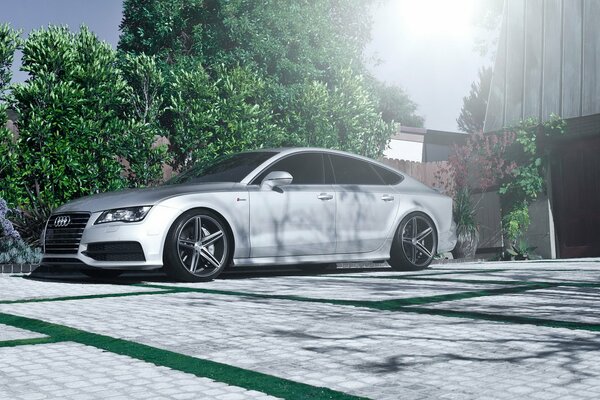 Silver Audi with alloy wheels near the tree