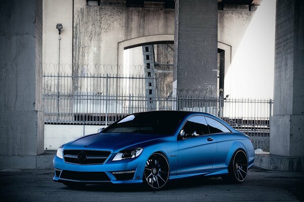 Blue car on the bridge behind the fence