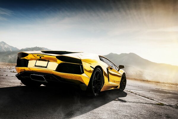 El coche dorado de Lamborghini en el fondo de las montañas