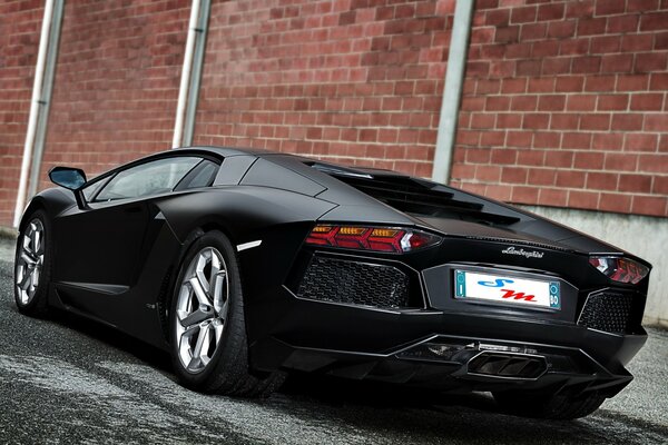 Lamborghini negro mate en la pared de ladrillo