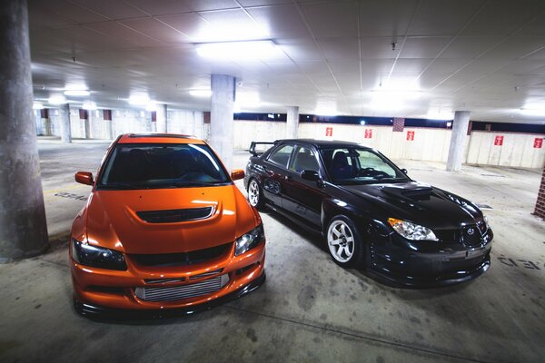Orange mitshubishi et subaru noir sur le parking