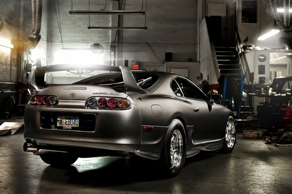 A gray Toyota in the middle of the garage. Rear view