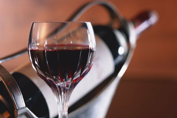 A glass of red wine on the background of a bottle