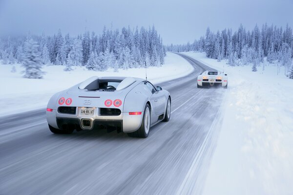 El Bugatti Veyron blanco en la tracción delantera realiza el tráfico en la carretera de invierno