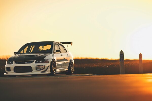 Voiture Mitsubishi couleur blanche sur fond de coucher de soleil