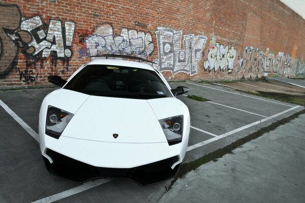 Front view of a white Lamborghini with trapezoidal headlights in the parking lot