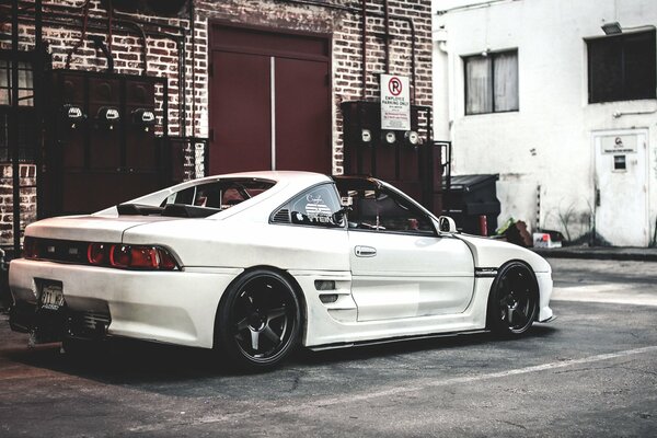 Weißer Toyota mr2 auf Backsteinhaus Hintergrund