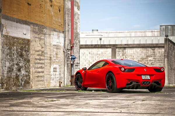 Ferrari rossa vicino al muro di mattoni