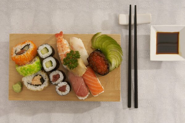 Sushi i bułki na tacy z paluszkami i sosem