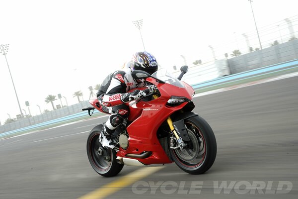 A racer is racing at speed on his motorcycle