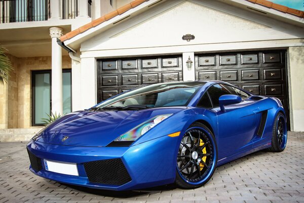 A blue Lamborghini car is parked near the house