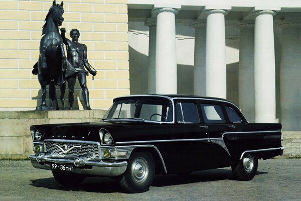 Un coche negro junto a una estatua de un hombre con un caballo