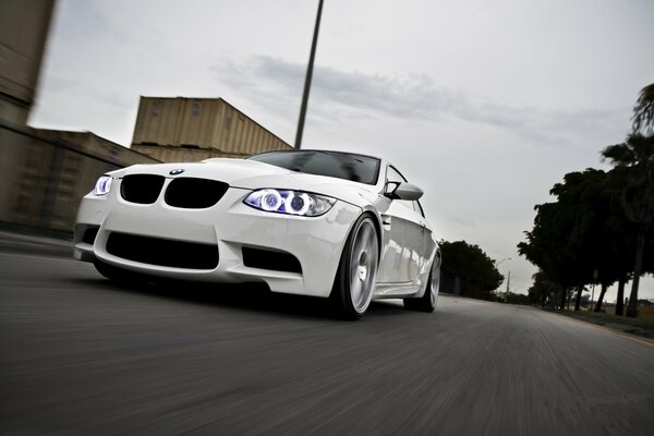 Une bmw blanche roule sur une route urbaine