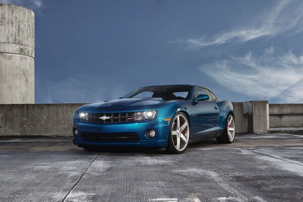 Chevrolet camaro blue in the parking lot under the clouds