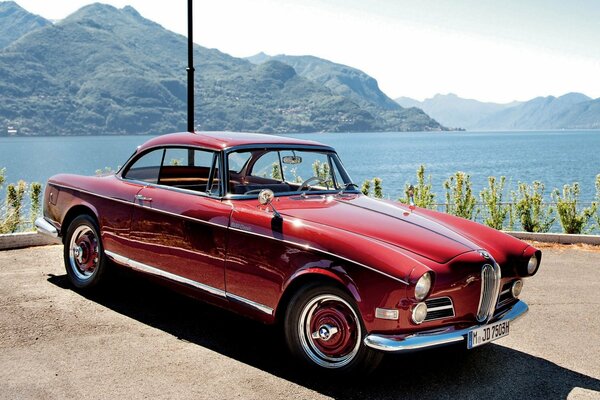 Rosso bmw 1956 sullo sfondo di montagne e fiumi