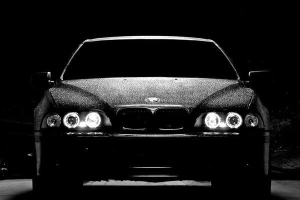 Laconic BMW M5 at night with the headlights on