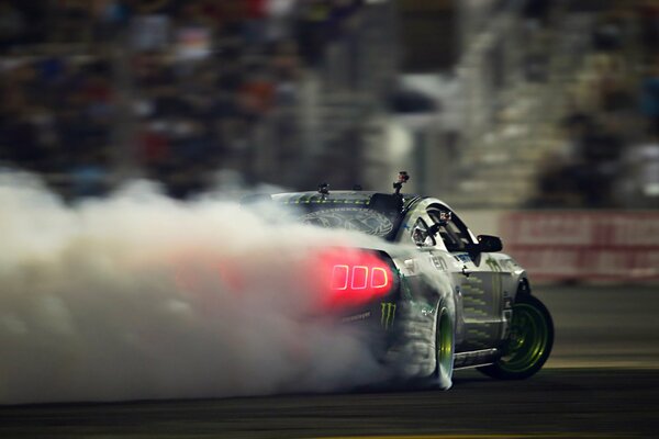 A tuned Ford Mustang shines through the smoke from the tires