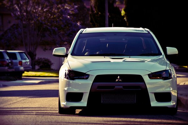 A white Mitsubishi is parked on the side of the road