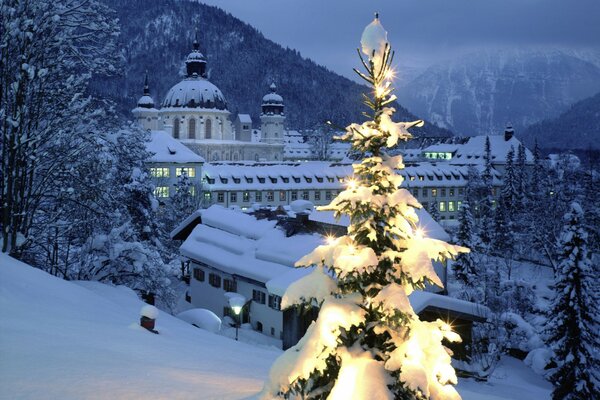 Albero di Natale con illuminazione sullo sfondo di una città innevata