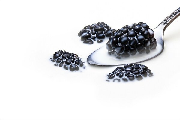 Blackberries on a spoon in a plate with milk