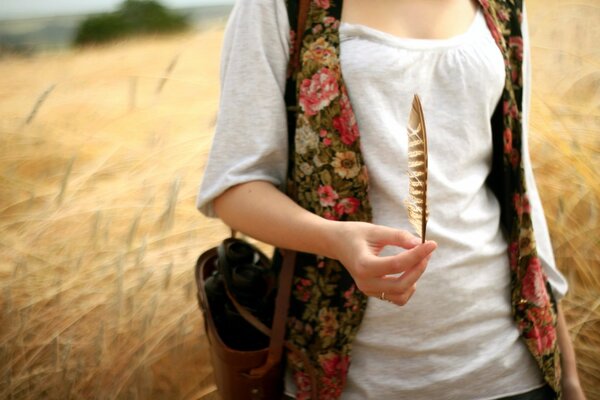 The girl standing in the field holds a pen