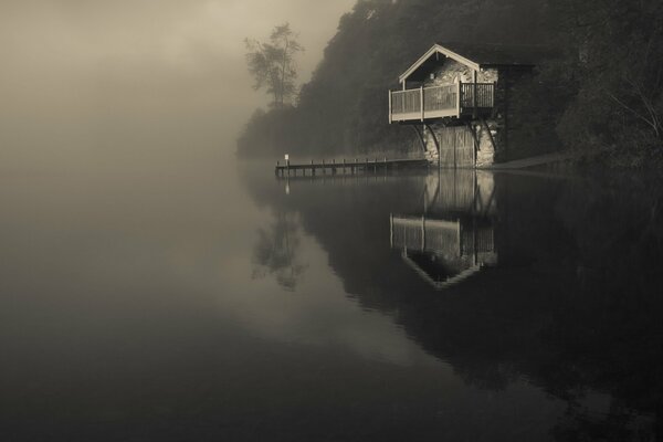 Lago en la niebla con una casa solitaria
