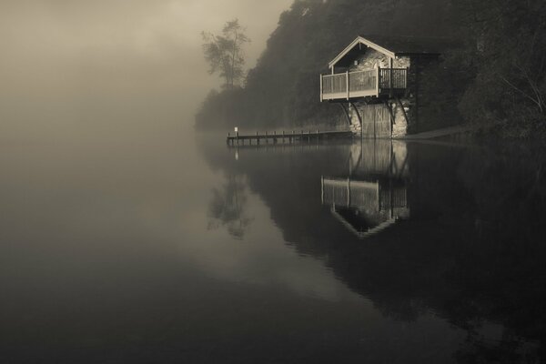 Lac dans le brouillard avec une maison solitaire