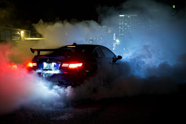 Bmw dans la nuit dans la fumée des pneus, vue arrière