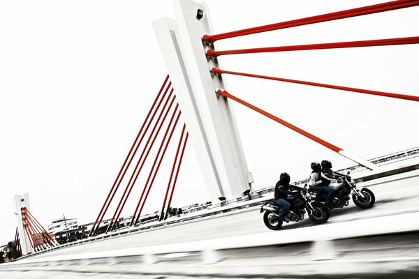 Motocykliści jeżdżą po moście białe tło