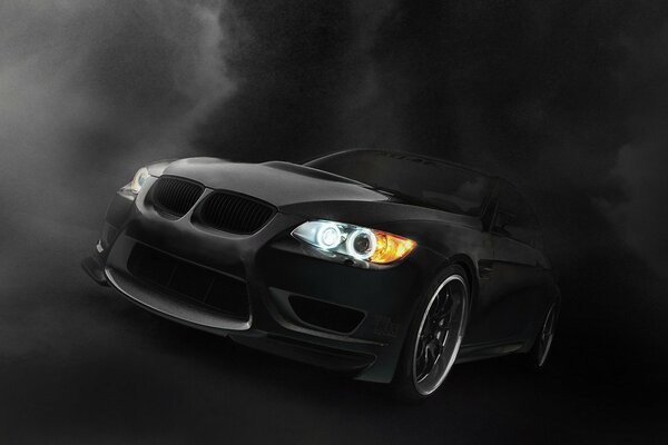 Schwarzer BMW glänzt mit Scheinwerfern im Dunkeln