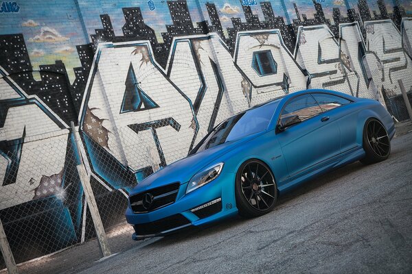 Mercedes-Benz mit coolem Tuning auf dem Hintergrund von Graffiti am Zaun