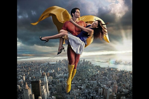 Superman holds a girl in his arms over the city