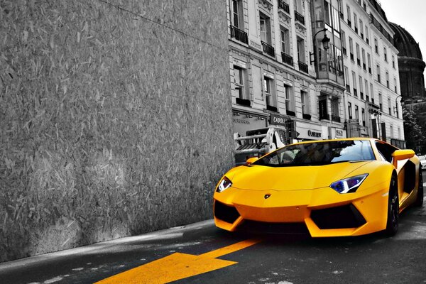 Gelber Lamborghini auf der Straße in einer schwarz-weißen Stadt