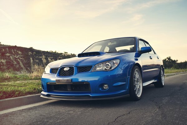 Azul Subaru Impreza en la pista entre las colinas