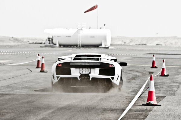 Lamborghini blanco en la pista de carreras vuela levantando polvo
