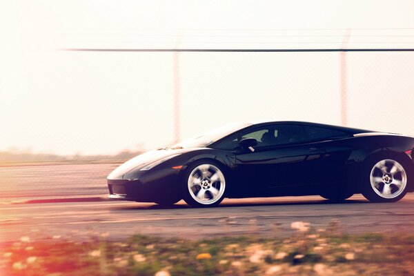 Black Lamborghini at speed on the track